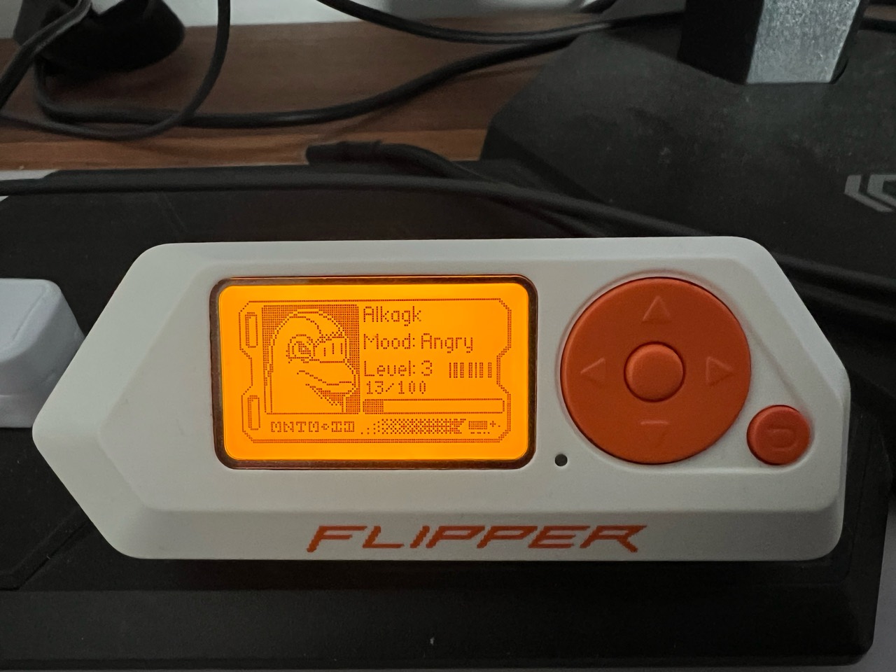 Flipper Zero on a desk showing its dolphin profile, level 3 and an angry mood