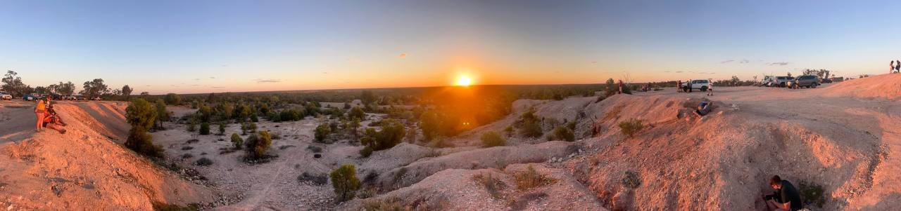 Panoramic view of the sun setting over the eroded ridges and mullock heaps of the opal fields